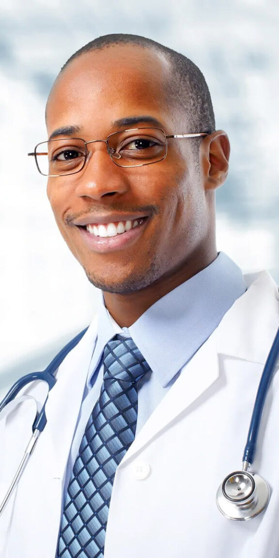 An African-American doctor wearing a white coat and tie. He is smiling.